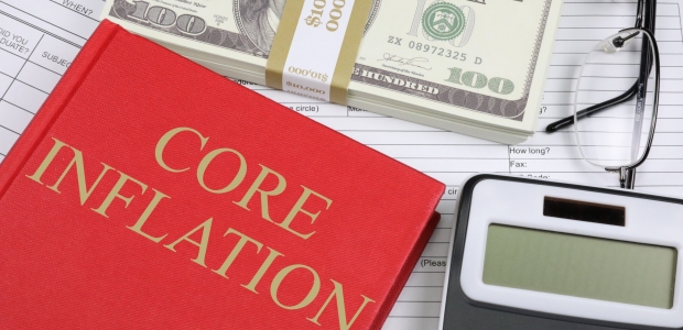 a stack of money next to a book on inflation and a calculator
